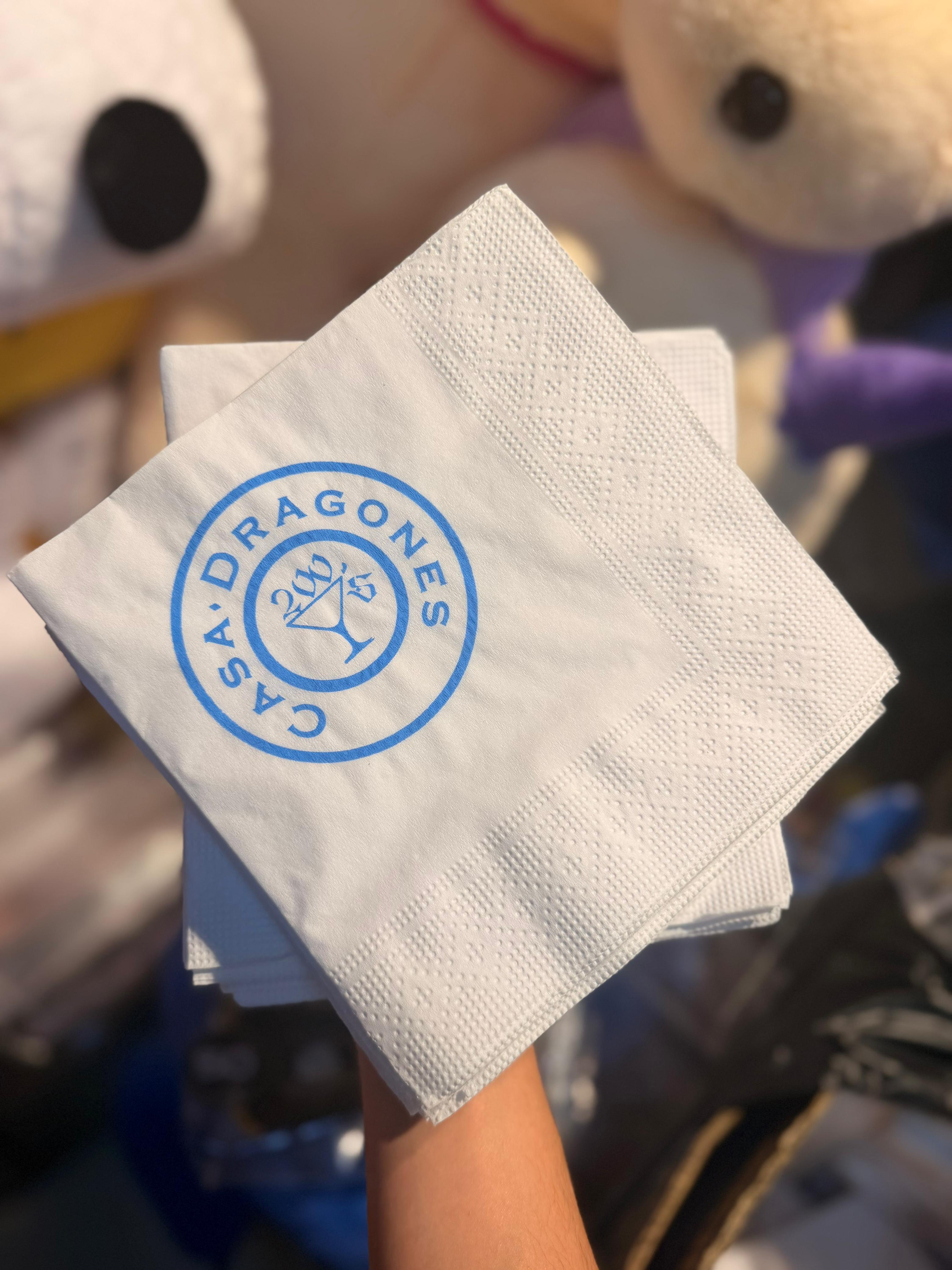 Servilletas Casa Dragones marcadas tipográficamente en lujo, sostenidas en mano frente al taller