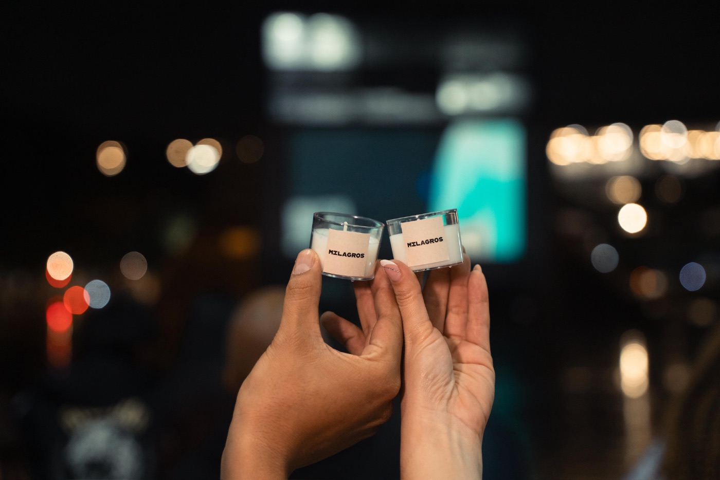 Dos velas Milagros sostenidas en el aire con luces de fondo del evento