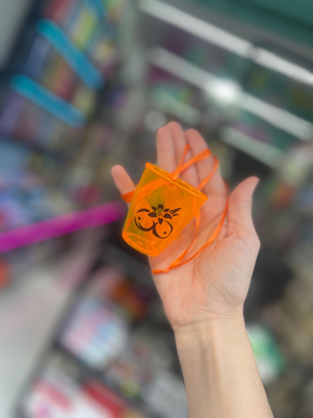 Vasito Tropicoqueta con cordón naranja sobre la mano