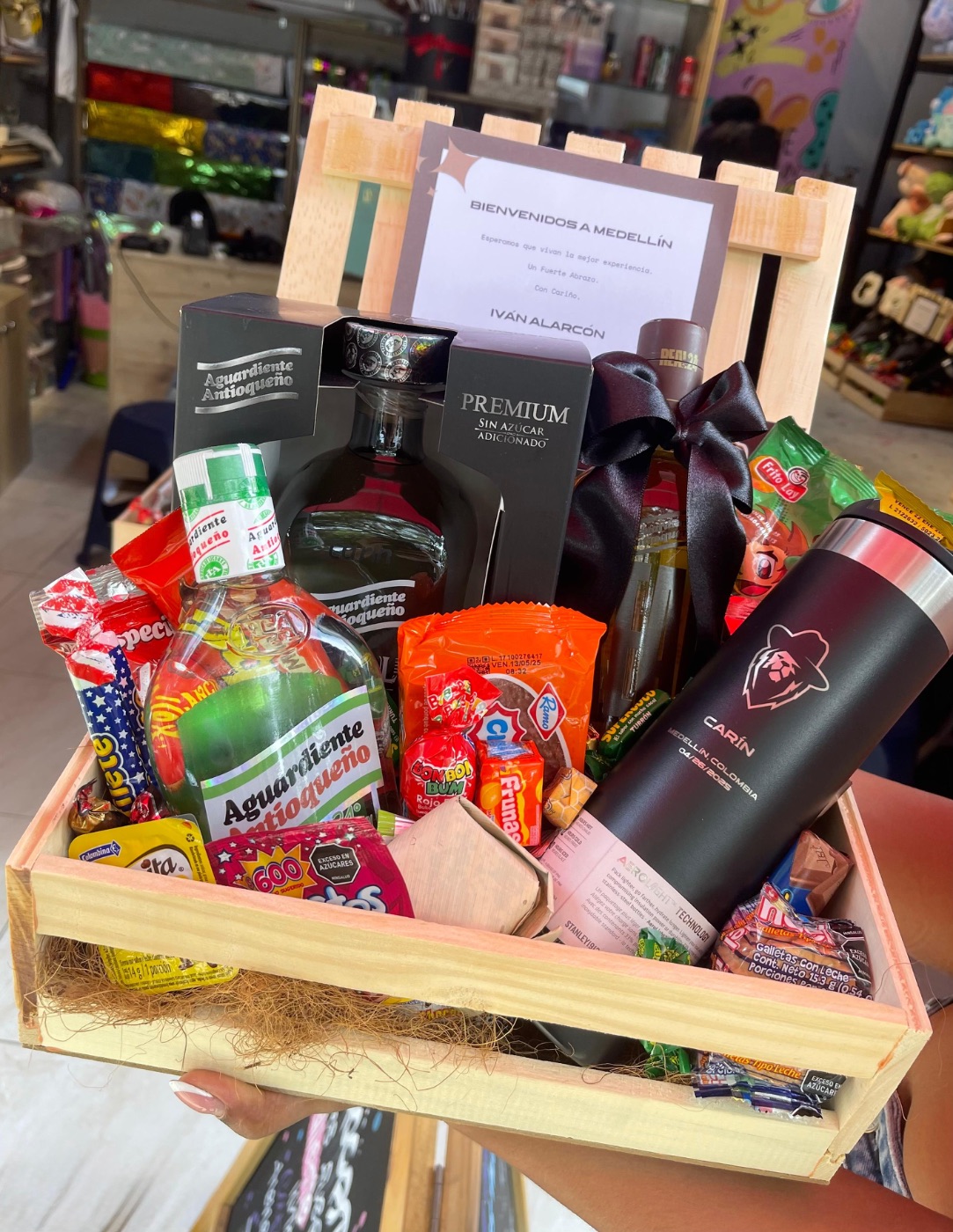 Detalle de ancheta — aguardiente Antioqueño, dulces colombianos y termo brandeado Carín en caja de madera