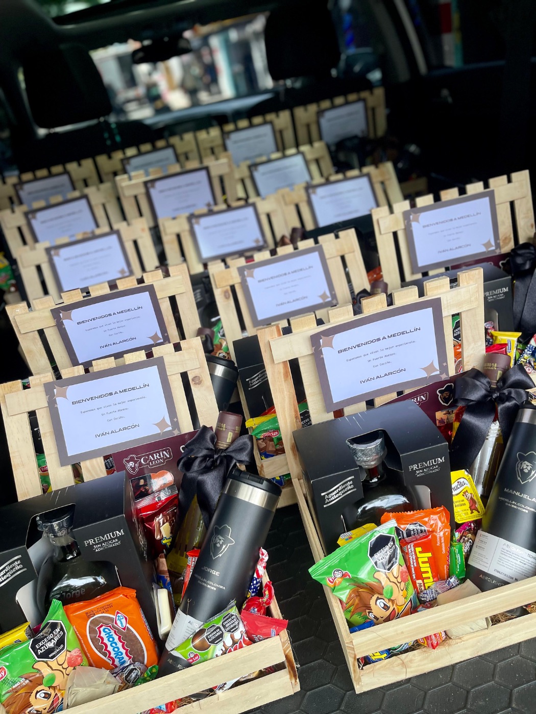 Anchetas de bienvenida Carín León en línea — múltiples cajas de madera con productos colombianos en cajuela